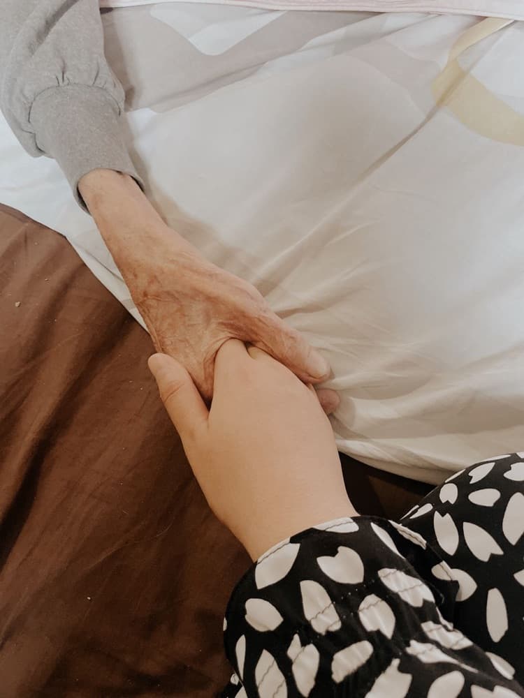 Une main tenant celle d'un patient — accompagnement palliatif à domicile à Tournai